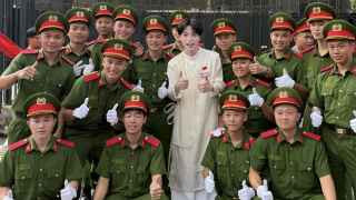 Дык Фук (в центре, в белом платье), открытый гей, подходяще увлекается милитаристской тематикой