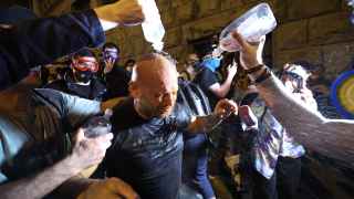 Протестующие поливают водой мужчину, в которого попали слезоточивым газом.